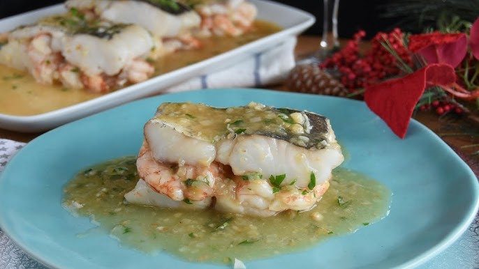 Plato de bacalao con gambas en salsa, decorado con hierbas y un toque festivo.