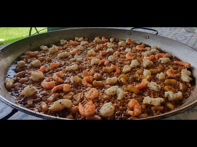 Paella con mariscos, verduras y arroz en una gran sartén.