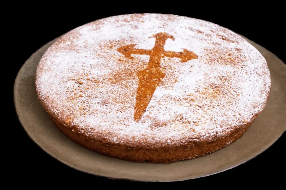 Bizcocho redondo con un diseño de cruz en azúcar glas sobre la superficie.