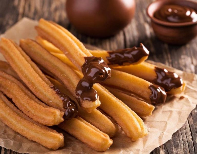 Churros dorados acompañados de chocolate para mojar.