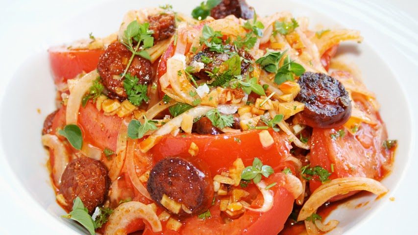 Ensalada keto Plato de pasta con chorizo, tomate, cebolla y hierbas frescas.