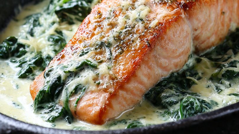 Filete de salmón cocido sobre espinacas en salsa cremosa.