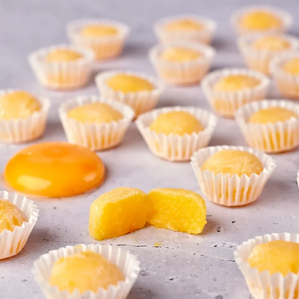 Mini pasteles de color amarillo en moldes de papel, con yema de huevo en el centro.